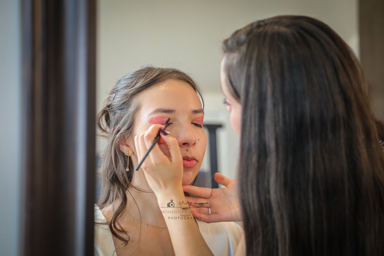 Makeup artist applying eyeshadow to bride before wedding ceremony.